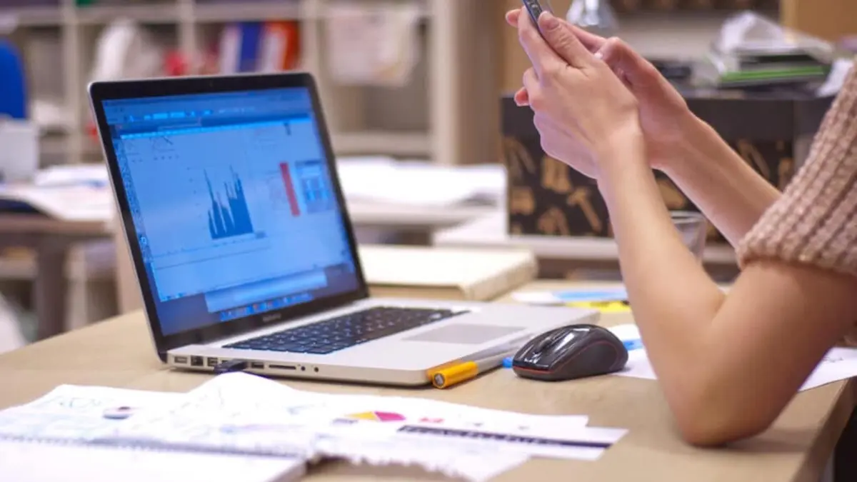 Trabajadora frente a ordenador con datos de productividad en la pantalla.