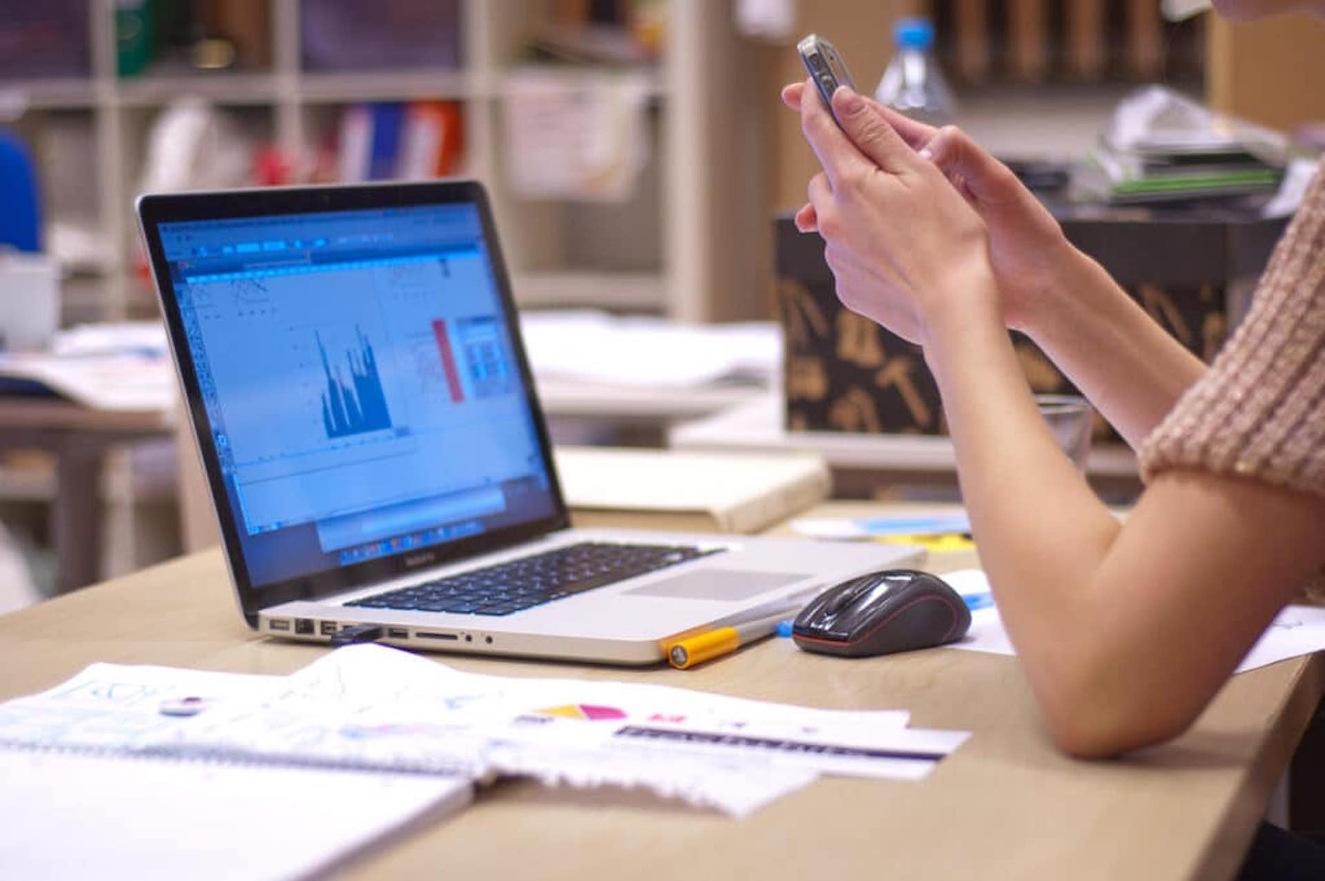Trabajadora frente a ordenador con datos de productividad en la pantalla.